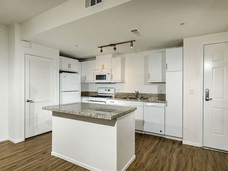 Spacious kitchen with an island and three lights on top of the ceilling