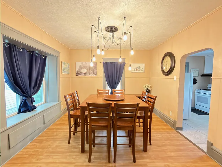 Dedicated dining area with a full-size table, large windows, and statement pendant lighting, open to the kitchen.