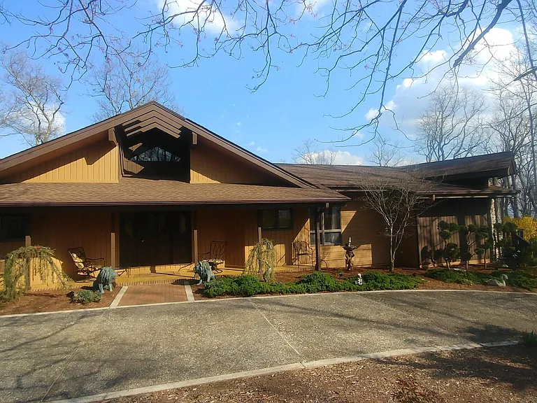 Front of house with large circular driveway and beautiful landscaping