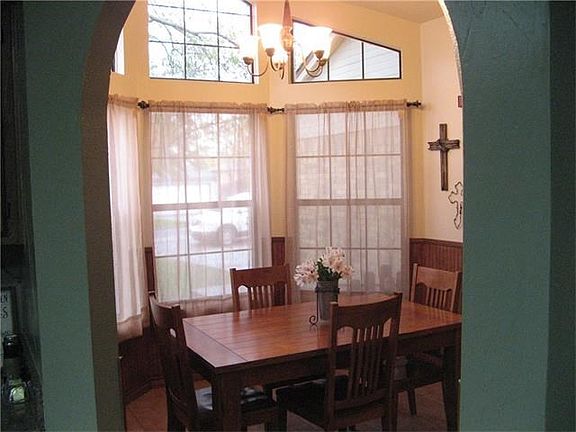 This dining area has lots of natural light, added wains coat, and hard tile.
