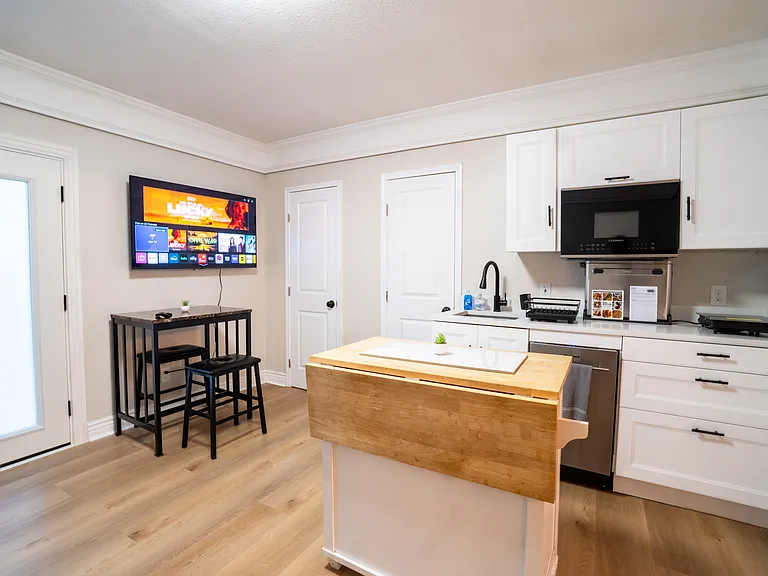 Kitchen with electric stovetop, microwave, refrigerator, dishwasher, & toaster oven/air fryer.