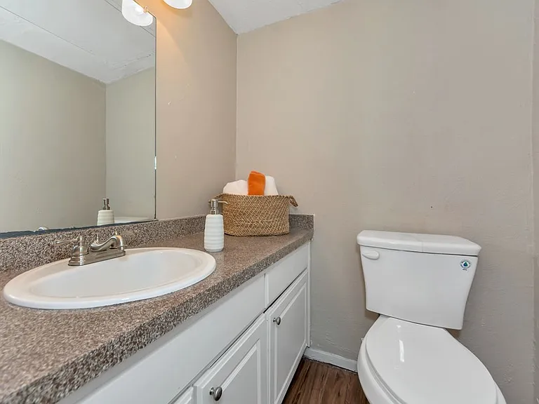 Bright bathroom with modern vanity, granite-style countertop, and full-size mirror at Watersong Villas Apartments.