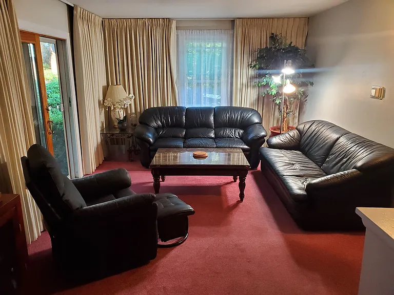 Spacious living room with multiple seating areas, large windows with drapes, and a coffee table for private lounging.