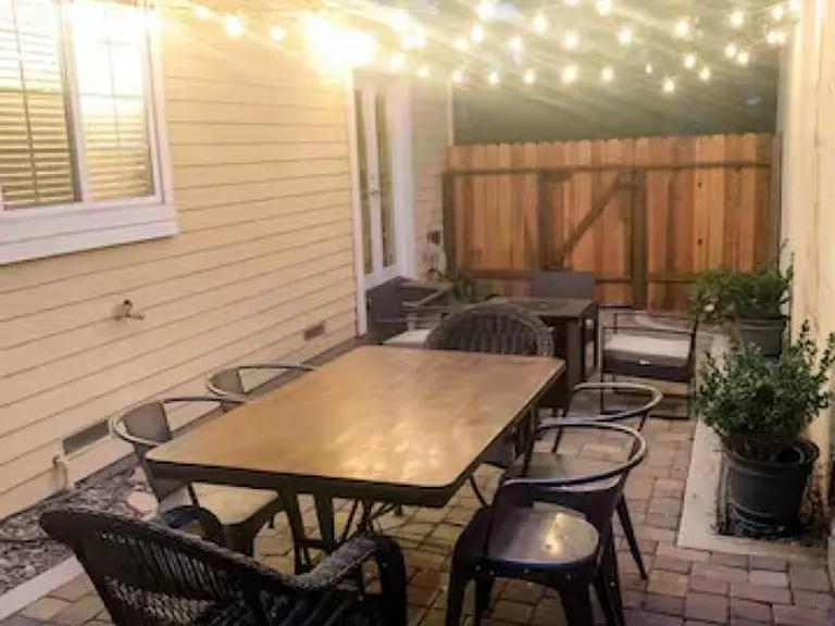 Courtyard patio with string lights, dining table, and fire pit.