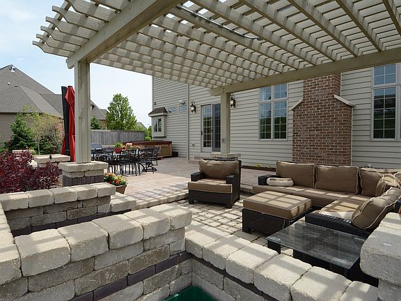 Stamped concrete patio with several sitting areas. Pergola has a fireplace