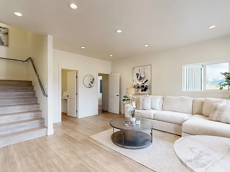 Separate private sitting area featuring a large flat-screen TV, its own private entrance, and an adjacent powder room, with natural light and mountain views creating a warm and inviting atmosphere that leads to the private upstairs suite.