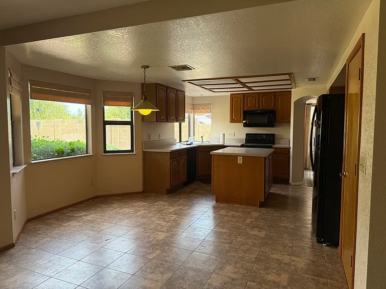 Kitchen with black appliances, kitchen island with storage and separate pantry. Room for kitchen table.