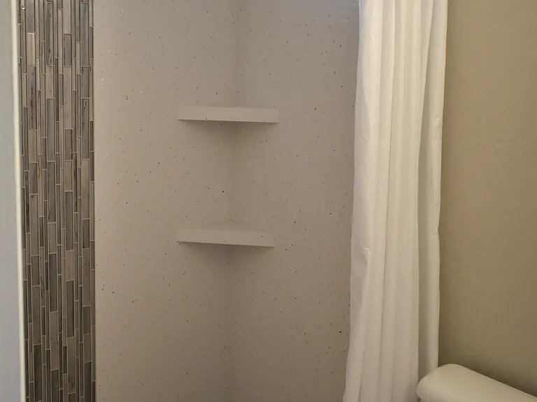 Master Bathroom - Walkin shower with solid-surface surround, mosaic tile accents, built-in shelves, and fixtures - installed Aug 2024.