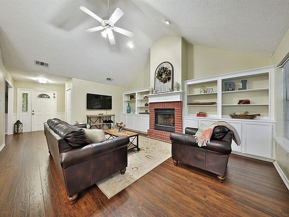 Large living area with vaulted ceiling, built-ins, gas-log fireplace, gorgeous wood-grain laminate flooring.