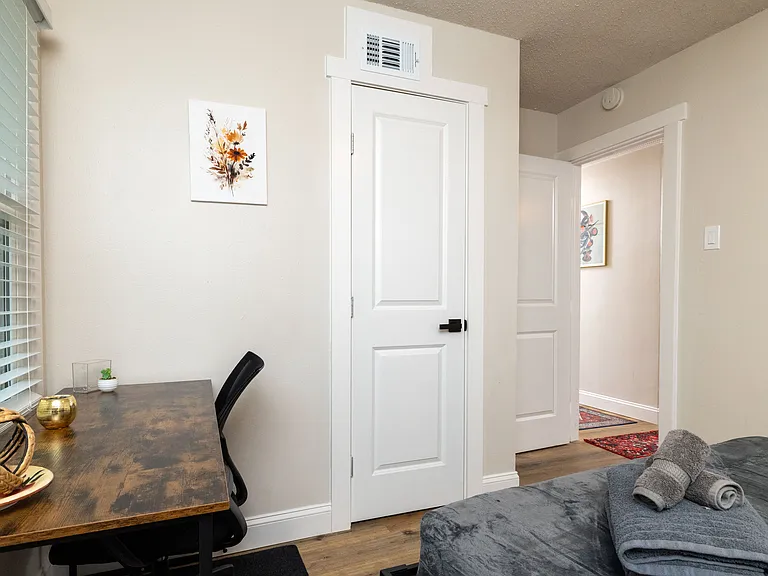 Cozy dedicated workspace featuring a rustic wood desk, ergonomic chair, and soft natural light. Located in a bedroom 3 with fresh linens and easy access to the hallway_perfect for focused work and relaxing stays.