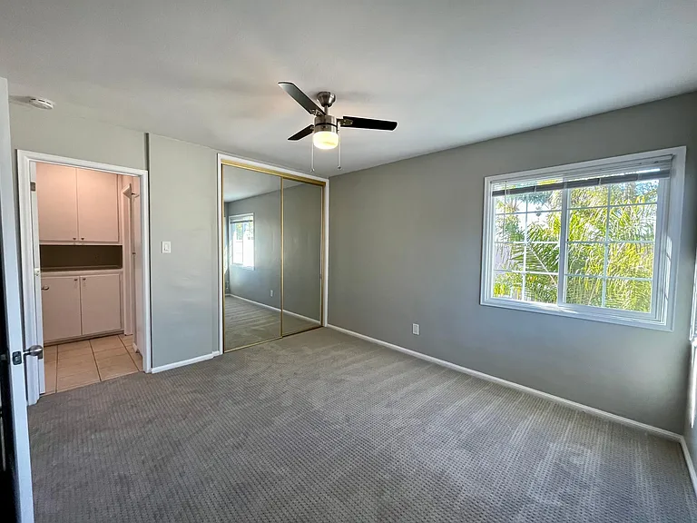 Bedroom with large closet, lots of natural light from west and north facing dual paned windows. View into the hallway with linen cabinet and utility cabinet.