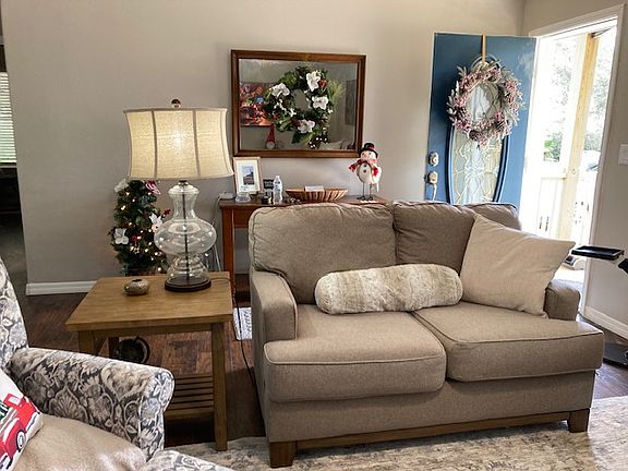 Front door has a storm door so you can enjoy letting in natural light without letting the dog out or the bugs in, A foyer table is perfect spot to drop keys and a welcome entrance into the house. Leads you into the Living room. Love seat pic