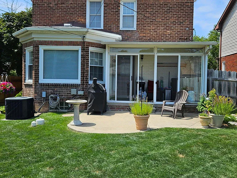 Rear View from Yard with enclosed porch leading to a full ground level patio.