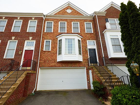 The front view features a beautiful brick exterior, a charming bay window with PVC frames, a welcoming entry with steps leading to the front door, and two-car garage.