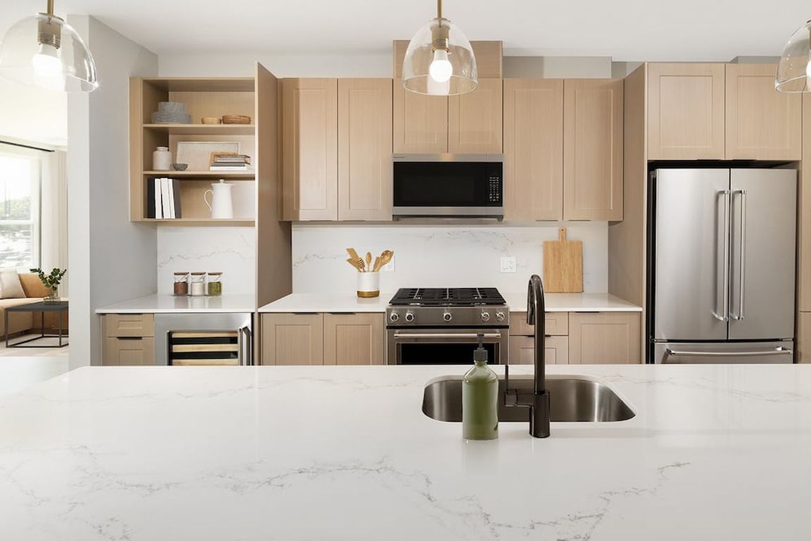 Signature Collection Kitchen with oak shaker cabinetry, marbled white quartz countertop and backsplash, and upgraded stainless steel appliances