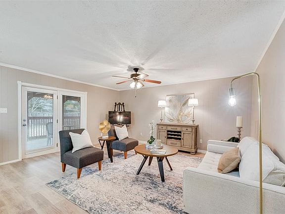 Living room featuring a textured ceiling, ornamental molding, ceiling fan, and light wood-type flooring