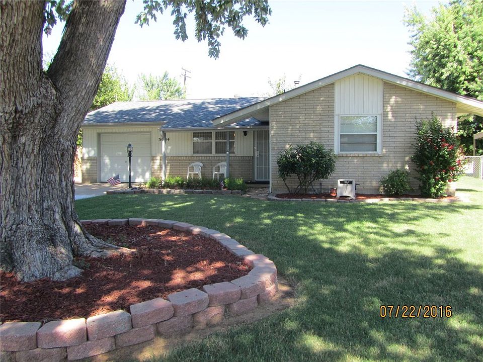 Beautiful front view with fabulous landscaping, large shade tree, and covered front porch.