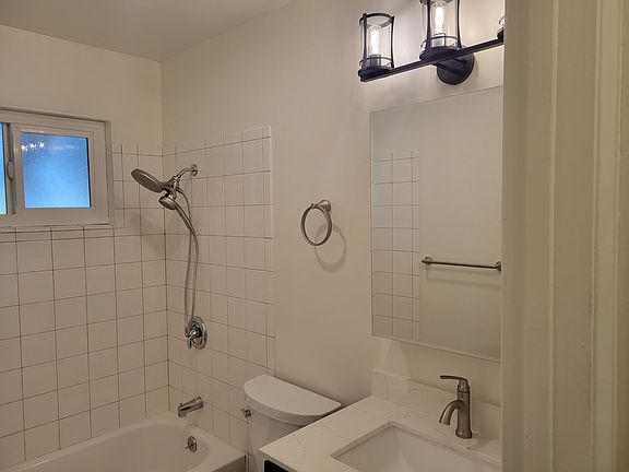 Remodeled bathroom with smooth ceramic tiles and new light fixtures.