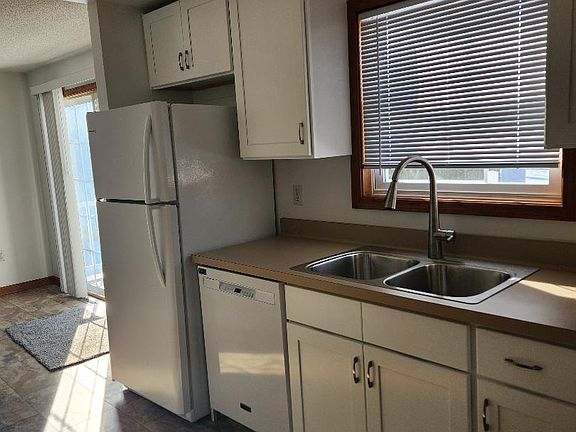 Kitchen with new flooring, cabinets, counter top, sink, window blinds & appliances.