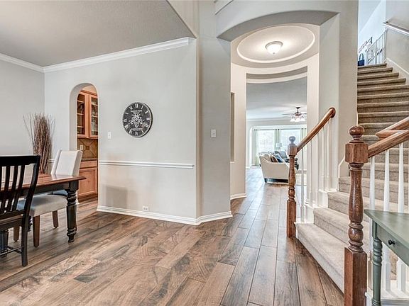 Foyer view. Handsome details from the mill work in the dining room to the butler pantry with glass cabinets and granite counter seen through the arched doorway. Notice the rotunda with art niches straight ahead and the curved staircase to the right.