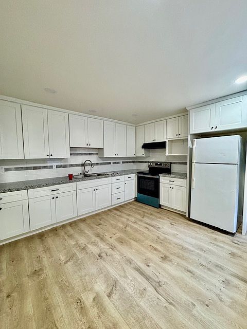 NEW Kitchen with new wood flooring. New cabinets, new sink, new stove.