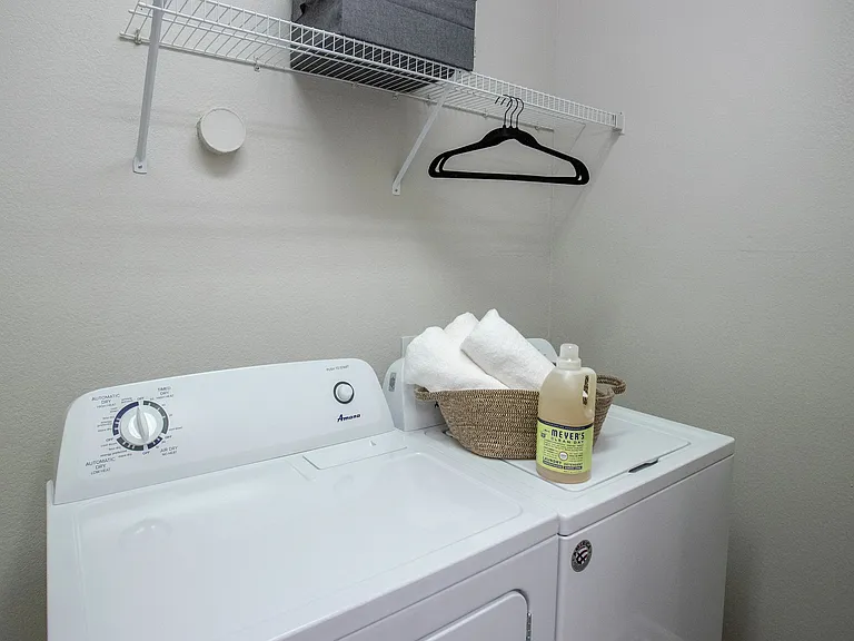 Enjoy the ease of in-home laundry with a full-size washer and dryer set, complete with additional overhead shelving for organized storage.
