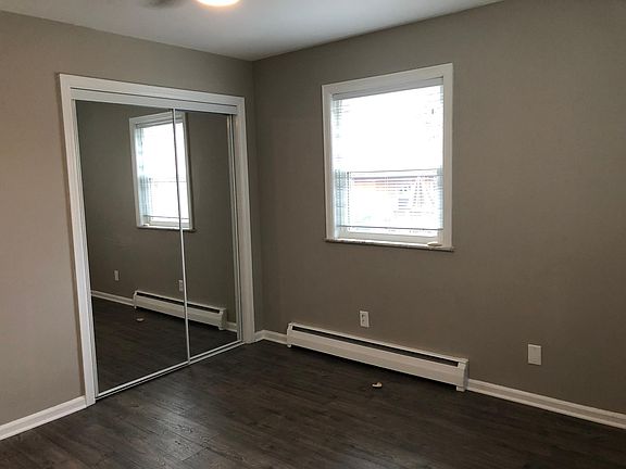 Bedroom with grey hardwood flooring and mirrored closet