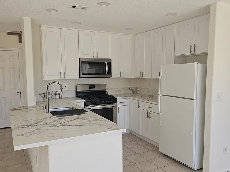 A well-appointed kitchen showcasing contemporary white cabinetry and sleek quartz countertops.