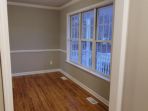 Formal dining room with newly refinished hardwood floors and windows overlooking the front porch and the spacious front lawn