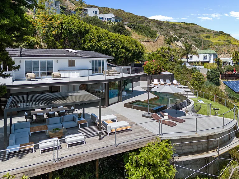 The outdoor area is a serene retreat, featuring expansive spaces for lounging, dining, and enjoying the view.