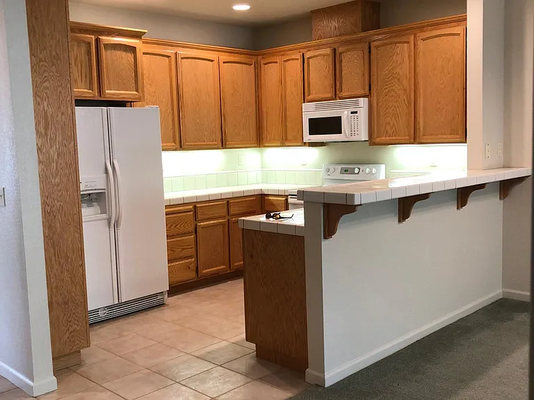Kitchen includes an electric range, microwave, dishwasher, refrigerator, garbage disposal and under cabinet lighting.
