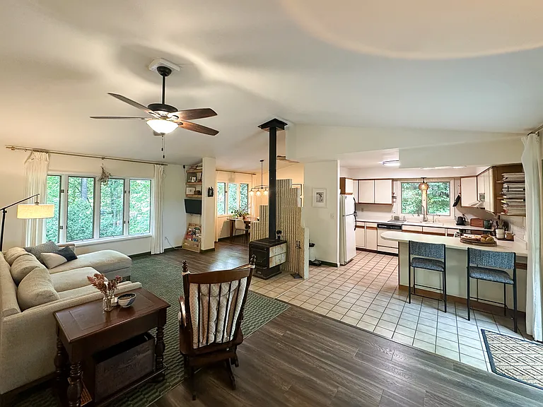 Open concept living area with vaulted ceiling and central wood stove