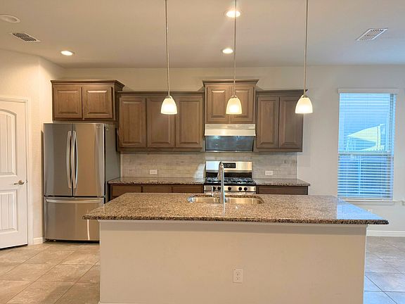 Kitchen with island and refrigerator comes with the home.
