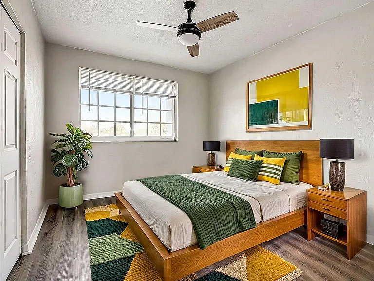 Bright and modern bedroom featuring a cozy wooden bed with colorful pillows, natural light streaming through large windows, and stylish decor, creating a welcoming and relaxing space.