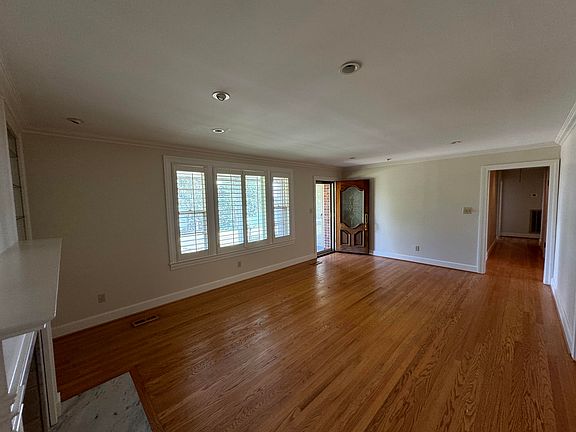 Living Room taken from corner by fireplace and built in bookcases and immaculate hardwood floors. Check out the wide plantation shutters!