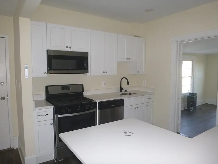 Newly renovated kitchen is about 10x10 with stainless steel appliances and white quartz countertops.