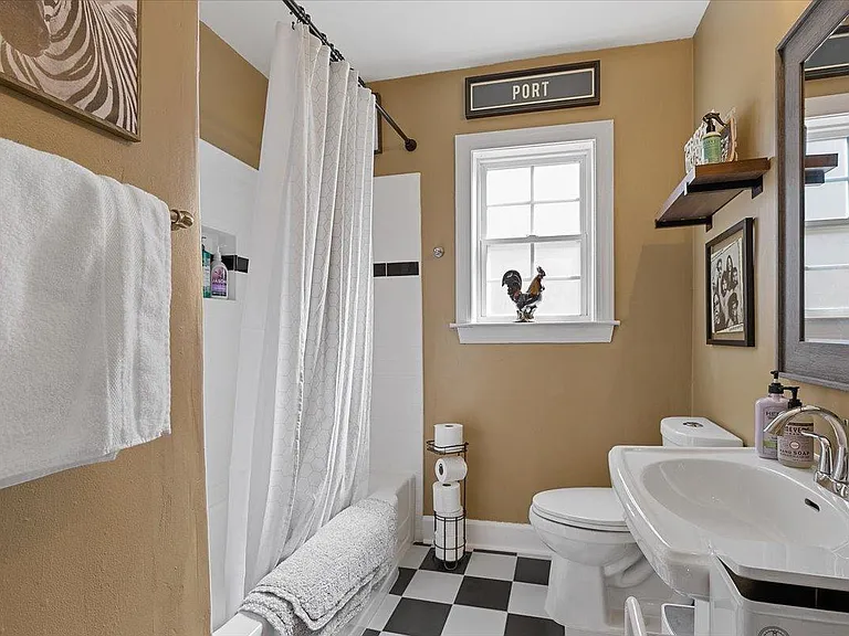 Modern bathroom at Hunsucker's Place, featuring updated fixtures, a full shower, and ample natural light. Conveniently located near Downtown Greensboro and Cone Health Hospital, this space combines functionality and comfort in a central, historic home.