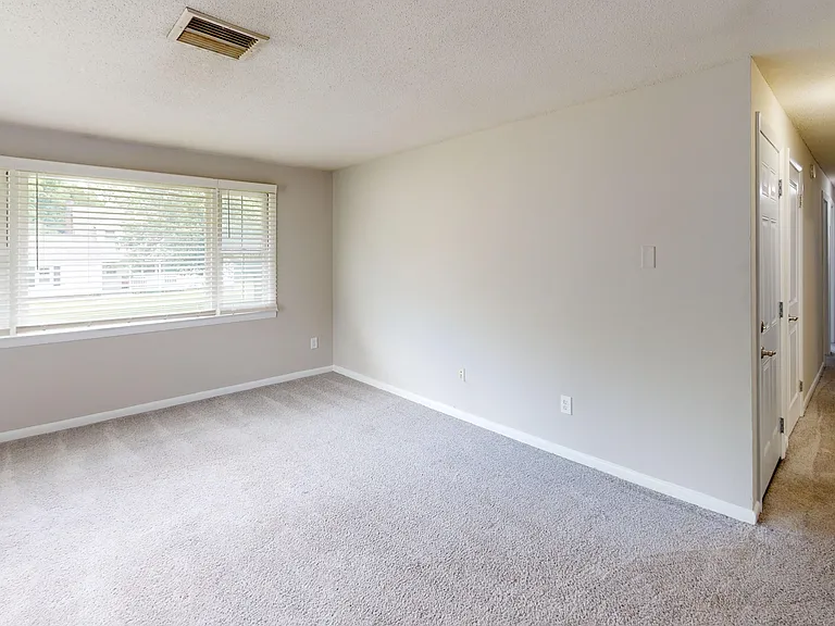 The Pioneer floor plan features a bright and open living room with plush carpeting and easy access to bedrooms and bathrooms down the hall.