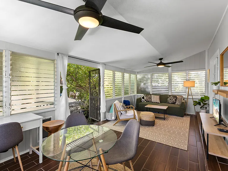 Enclosed lanai adds additional living space, a futon sofa, chair, TV, small dining set for 3-4, and a desk. Two large fans and lots of windows keep this area cool.