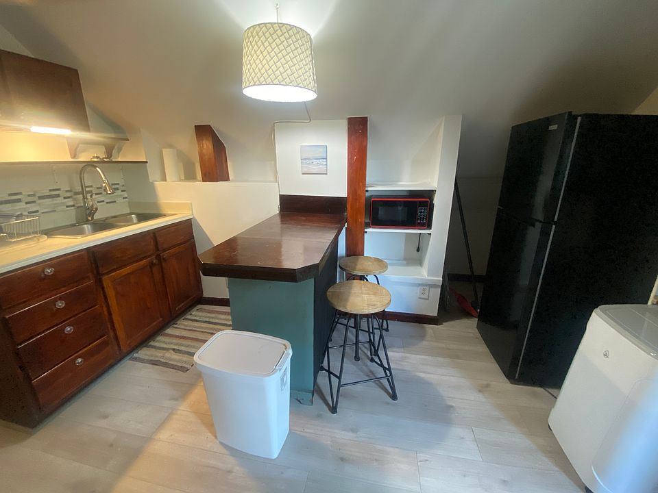 The kitchen has an island with two stools, new fridge w/freezer, new microwave, hot plate, dishes, utensils for cooking.