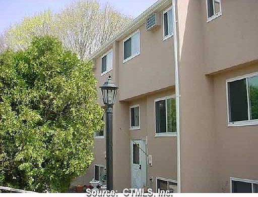 Exterior Front: Your approach with arborvitae hedge screening the parking