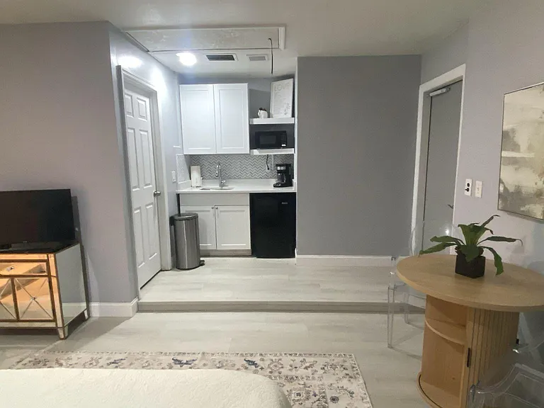 Private room with a kitchenette, including sink, cabinets, microwave, and mini fridge, plus a small dining area and TV.
