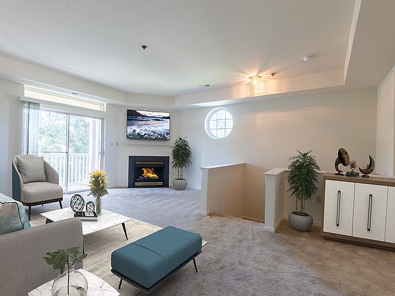 Second floor living room with bright windows, glass slider to balcony, gas fireplace and tray ceiling.
