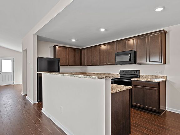 The kitchen features granite countertops and stunning wood cabinetry