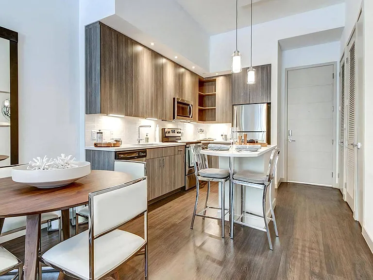 Kitchen With Bar Seating, Wood Cabinets, and Overhead Pendant Lights