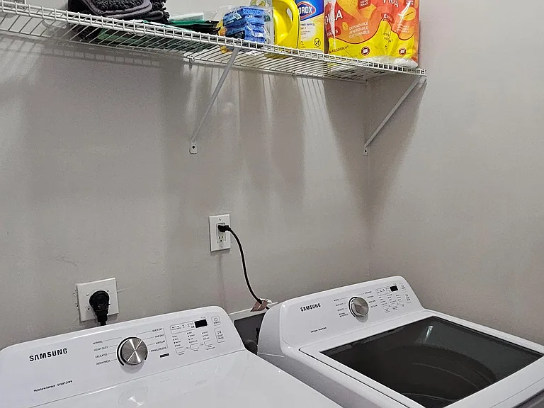Dedicated laundry area with Samsung washer and dryer, plus wire shelving for detergent, linens, and supply storage.
