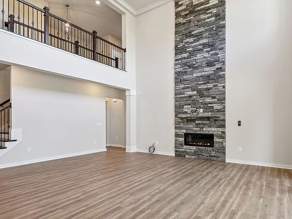 Two-story family room with stone fireplace and hardwood floors in Creighton in Fairway Estates