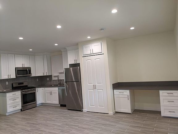 View of kitchen, stackable laundry cabinet and office desk