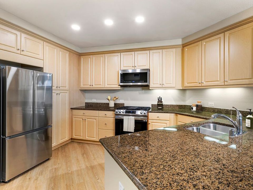 Renovated Package I kitchen with stainless steel appliances, brown speckled granite, oak cabinetry, and hard surface flooring