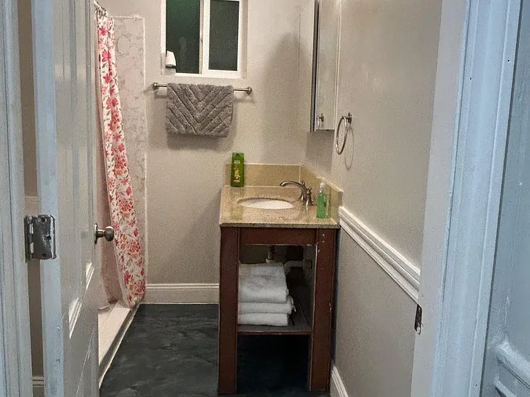 Compact full bath with tub/shower combo, vanity with storage, and a window for ventilation and natural light.
